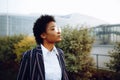 4k. Travel, Digital. A charming African American woman in an elegant striped suit, looks at the sky, and waiting for her