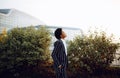 4k. Travel, Digital. A charming African American woman in an elegant striped suit, looks at the sky, and waiting for her
