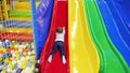 4k video of little toddler boy riding down on colorful palstic slide on playground at amusement park