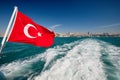 Turkish flag on a boat ÃÂ¸ Ships wake. The ship is leaving the big city. Royalty Free Stock Photo