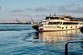 Kadikoy shore with pedestrian ferry turyol early in morning with haydarpasa commercial harbor cranes background.