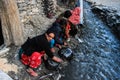 Poor Nepalese women traditionally wash dishes in a river in a village in the Himalayas