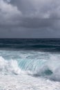 Azure wave turns into white surf under heavy cloudscape on Kaimu Beach, Hawaii, USA Royalty Free Stock Photo