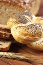 Kaiser bread roll with ear of rye on wooden table