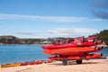 Kaiteriteri, New Zealand - July 2018: A trailer stacked with colourful red kayaks on a sandy beach, against a blue sea/sky