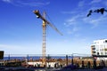 Yellow industrial crane with boom towards blue sky at summer time. Blue sea on the back