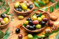 Kalamata, green and black olives in the wooden bowls. Food background. Top view