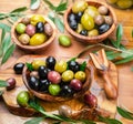 Kalamata, green and black olives in the wooden bowls on wooden table. Top view