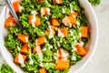 Kale and baked sweet potato salad with tahini dressing in white bowl, top view. Healthy vegan food concept Royalty Free Stock Photo