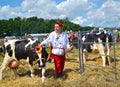 KALININGRAD REGION, RUSSIA. The farmer-cattle breeder conducts on a leash a cow of black and motley breed. Agricultural holiday