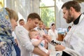 An Orthodox priest anoints an infant `s eel before diving into water. Baptism rite