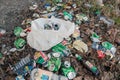In park area, among fallen leaves, scattered chaotically crumpled beer cans and empty bottles of alcohol