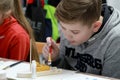 A boy paints a hull of a wooden boat. Children`s master class in the studio