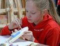 A girl paints the hull of a wooden boat. Children`s master class in the studio