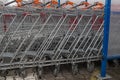 Row of metal shopping carts with orange handles standing tightly one in another outdoor in front of DIY store Royalty Free Stock Photo
