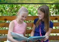 KALININGRAD, RUSSIA. Two cheerful girls read the book on a bench. The Russian text - Gulliver`s Travels