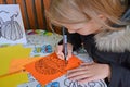 A girl draws a pumpkin with a marker on colored paper. Children`s master class in the open air