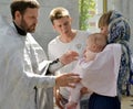 KALININGRAD, RUSSIA. An Orthodox priest gives away an infant godmother after immersion in water. Baptism rite