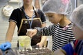 Girl pours white chocolate mass into molds. Children`s excursion to the Belgostar chocolate factory