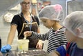 A girl takes a white chocolate mass for pouring into molds. Children`s excursion to the Belgostar chocolate factory Royalty Free Stock Photo