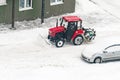 Kaluga, Russia - December 8, 2022: Tractor shoveling snow with a bucket in a car parking lot after a snowfall in winter Royalty Free Stock Photo