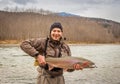 Kalum River, British Columbia, Canada - April 11th, 2017: An angler holding up a large steelhead, rainbow trout, on a cold river Royalty Free Stock Photo