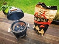 A kamado type barbeque grill with a bag of charcoal on a terrace