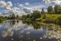 Kamenka river with floating lily pads and reflection of clouds on a sunny day Royalty Free Stock Photo