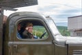 A little boy in the form of a Soviet soldier in the cockpit of an army car participates in a parade in honor of victory day