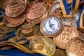 Many bronze medals with copper ribbons and yellow- blue ribbons on a silver tray, Champions awards, achievements in sport, the thi