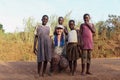 A young Caucasian European girl with blue pigtails surrounded by African poor children from the village