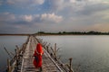 little girl with red dress, crosses old traditional bamboo wooden bridge across Mekong river