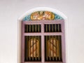 A colorful antique arched window painted light purple and elegant artwork in an