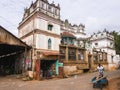 A worker pushes a cart on the street outside an old mansion in the village of