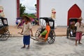 Kanchanaburi, Thailand, 09.09.2019: Beautiful Thai girl in traditional Thai, Siamese dress in an old rickshaw in front of the