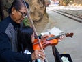 Kanchanaburi, Thailand - December 25,2516 : Asian musician violinist teaching young girl playing violin in public park.