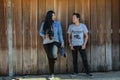 Young standing poses photographed with old wooden doors.