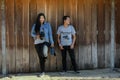 Young standing poses photographed with old wooden doors.