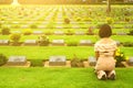 Asian woman sitting in front of black gravestone at graveyard with sunlight flare