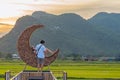 KANCHANABURI-THAILAND, SEPTEMBER 13, 2020 : Happy young couple take photo with crescent moon chair made of rattan for relaxation