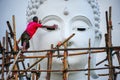 Worker renovating huge white Buddha Image