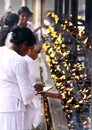 View on female Buddhist pilgrims light candles at altar