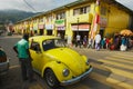 People in a vintage Volkswagen Beetle car pass by the street of Kandy, Sri Lanka.