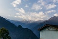 Kangchenjunga mountain with clouds above. Among green hills and house that view in the evening in North Sikkim, India