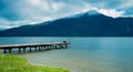 Kaniere Lake, New Zealand, October 7, 2019: Beautiful panorama of a loving couple sitting at the end of the pier admiring the Royalty Free Stock Photo