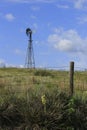 Kansas colorful landscape with a Windmill, blue sky, fence, and yuccas out in the country.