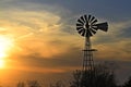Colorful Kansas Sunset with clouds, tree`s and a Windmill silhouette out in the country. Royalty Free Stock Photo