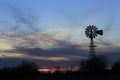 Colorful Kansas Sunset with clouds, tree`s and a Windmill silhouette out in the country. Royalty Free Stock Photo