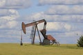 Kansas oil well Pump in a field with blue sky and white clouds Royalty Free Stock Photo