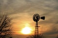 Kansas Sunset with colorful sky and clouds with a tree and windmill silhouettes out in the country.